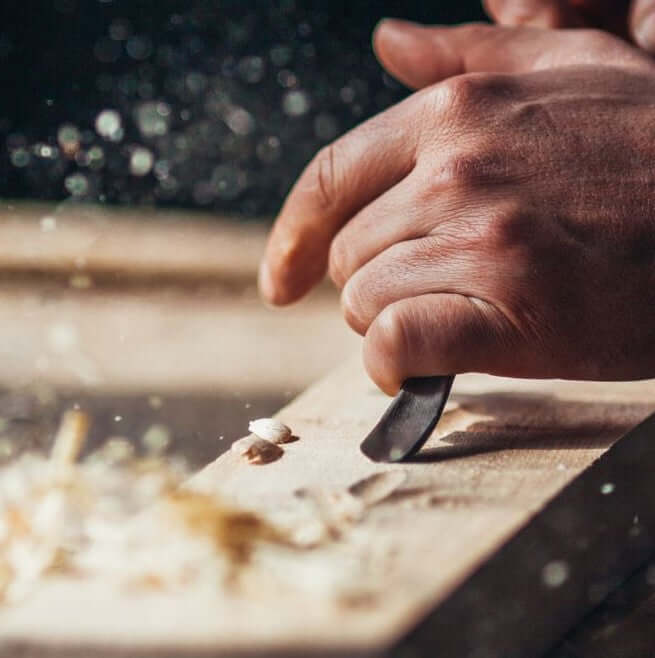 Close-up of a craftsman shaping wood with a chisel, showcasing quality woodworking tools from JM Online Tools.