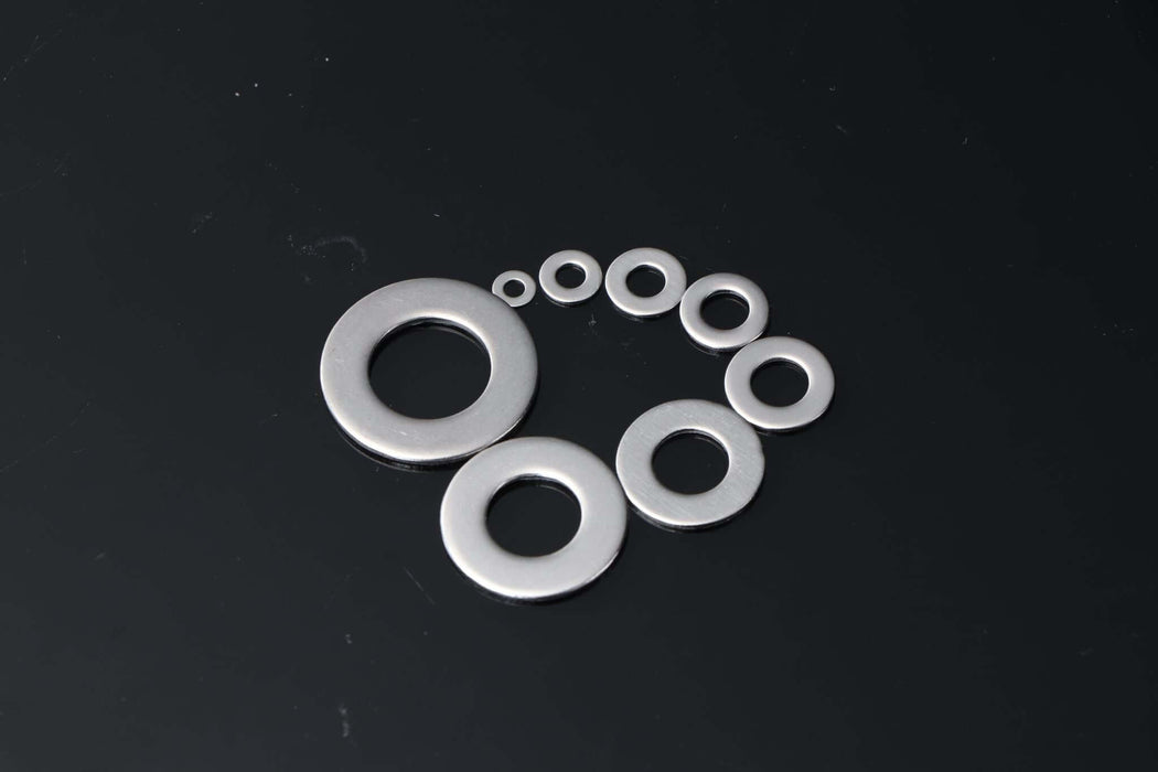 Stainless steel washers in various sizes arranged on a black background