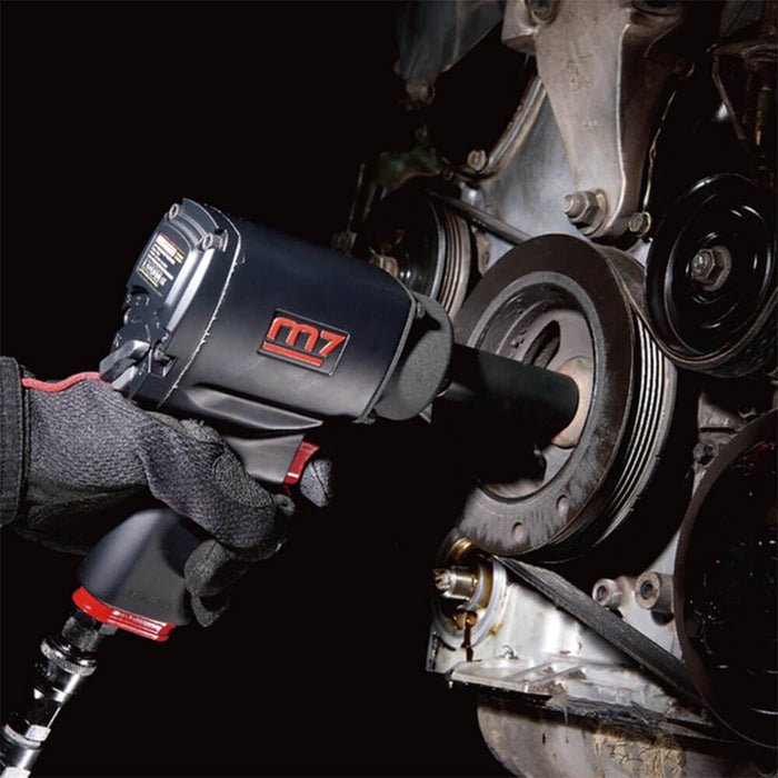 M7 Quiet-Series 1/2" Drive Air Impact Wrench being used on an engine for automotive repairs in a dimly lit setting.