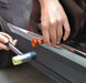 Hands using a small dent removal tool on a car, showcasing the repair process with a hammer and dent hook.