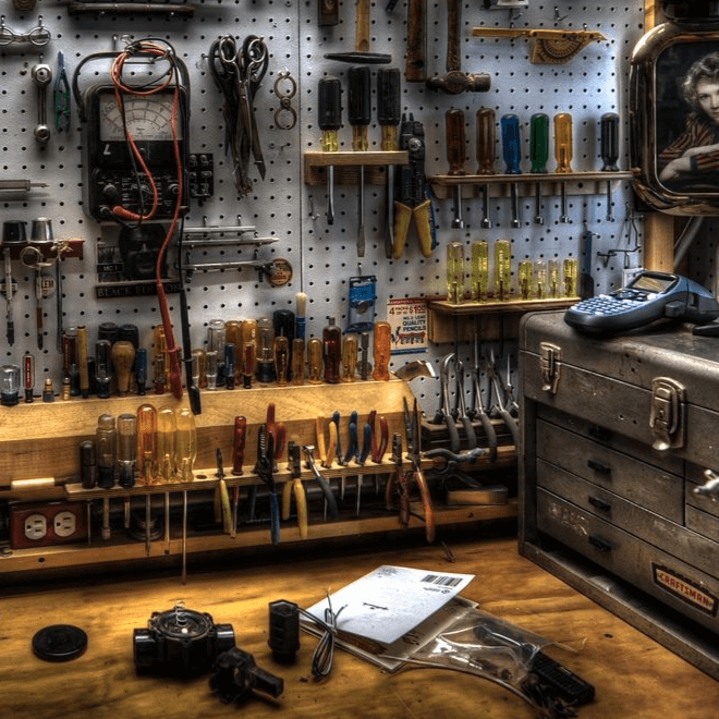 A well-organized workbench with tools neatly arranged on a pegboard, featuring screwdrivers, pliers, and electrical equipment in a workshop.